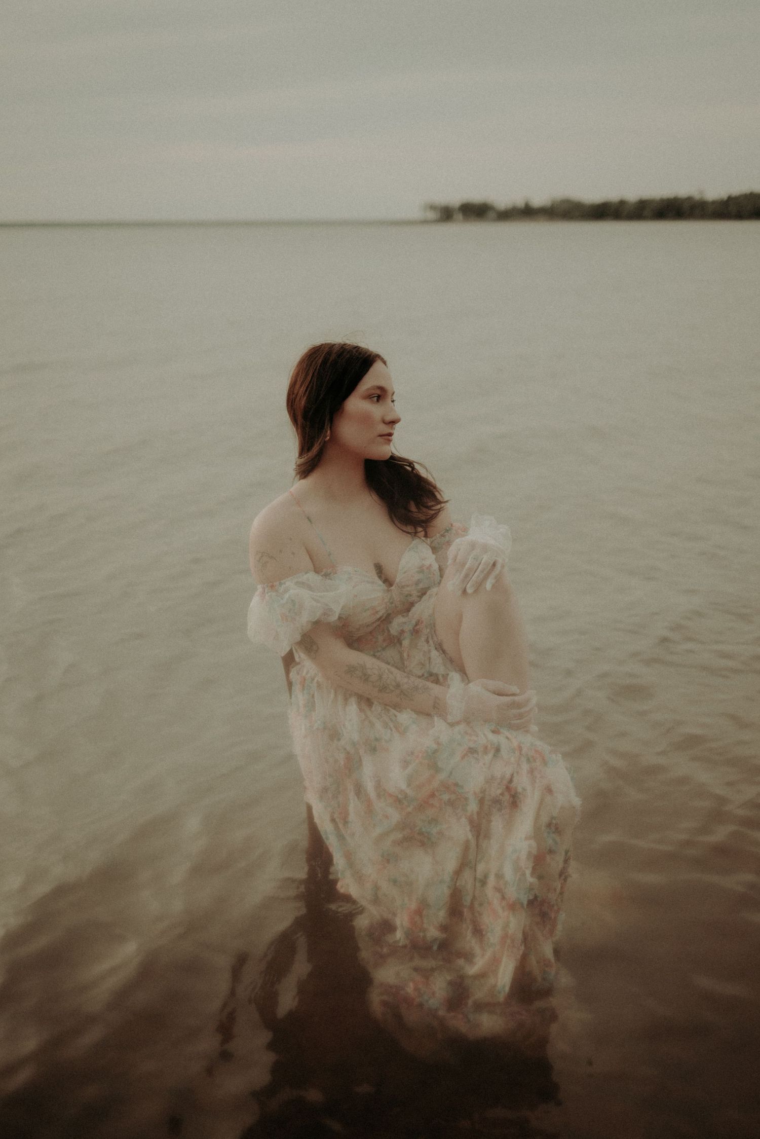 An ethereal water portrait with soft muted tones and a delicate lace gown.