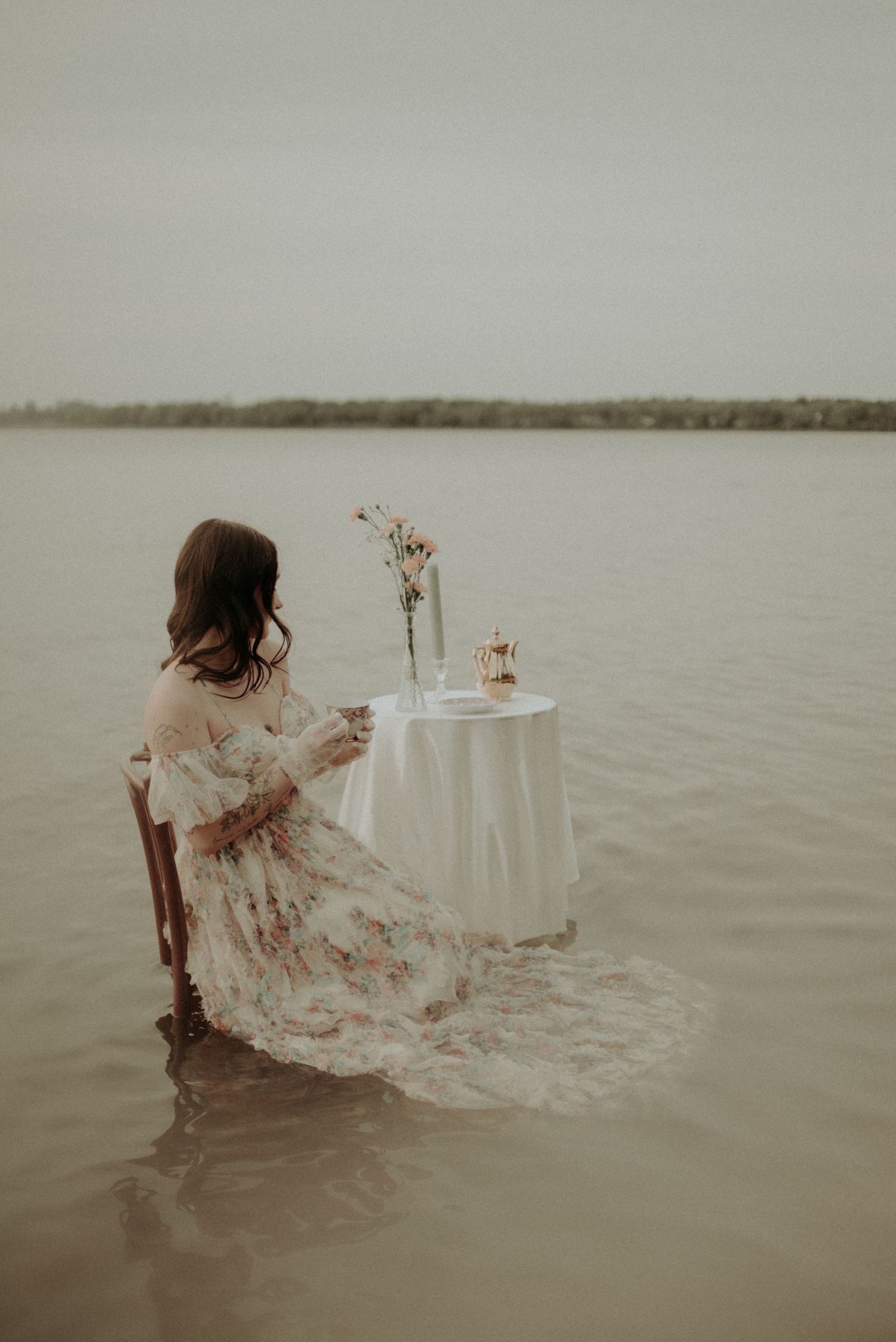 Artistic water scene with flowing dress and elegant table setting in natural light.