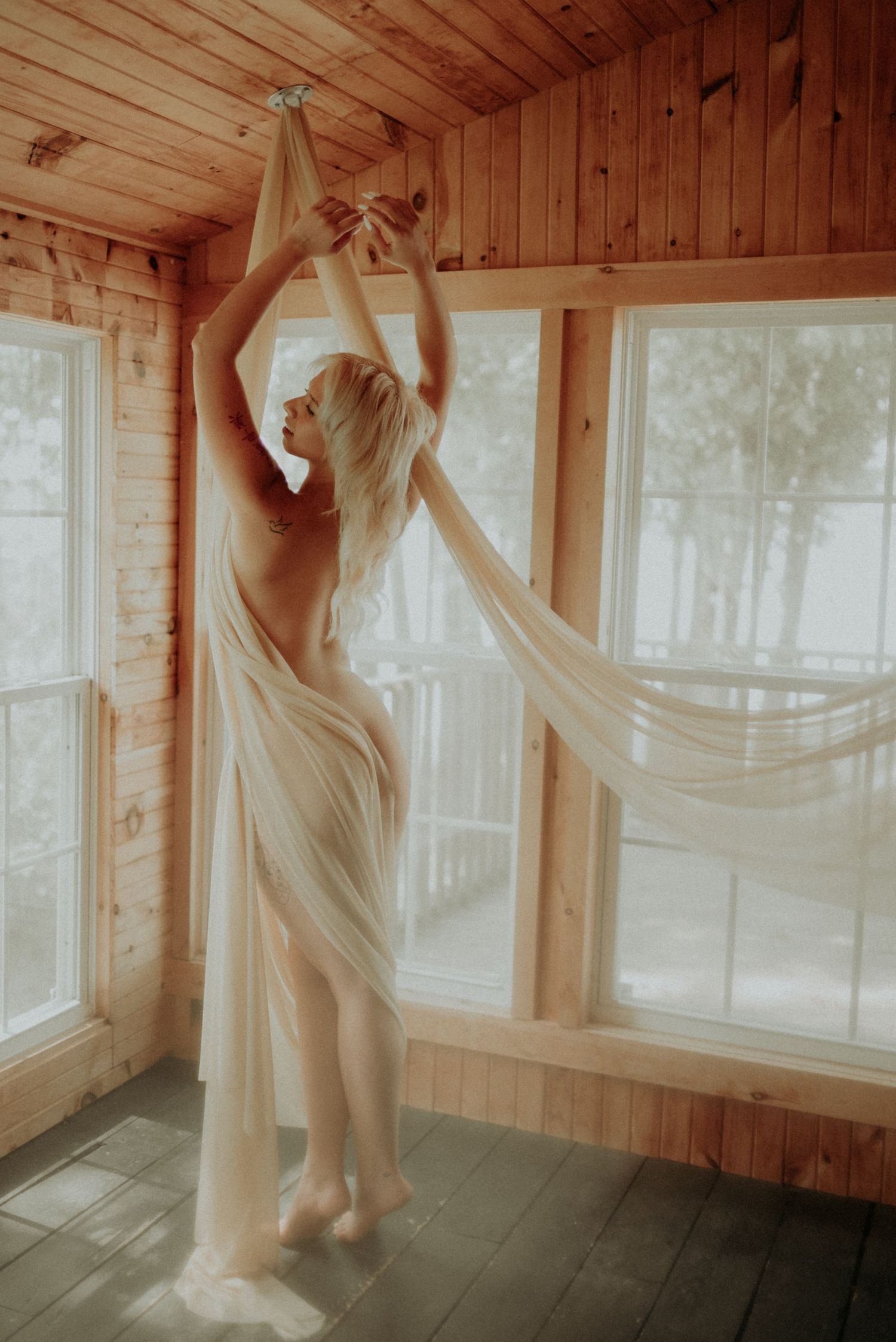 Elegant movement study with draped fabric in rustic wooden room.