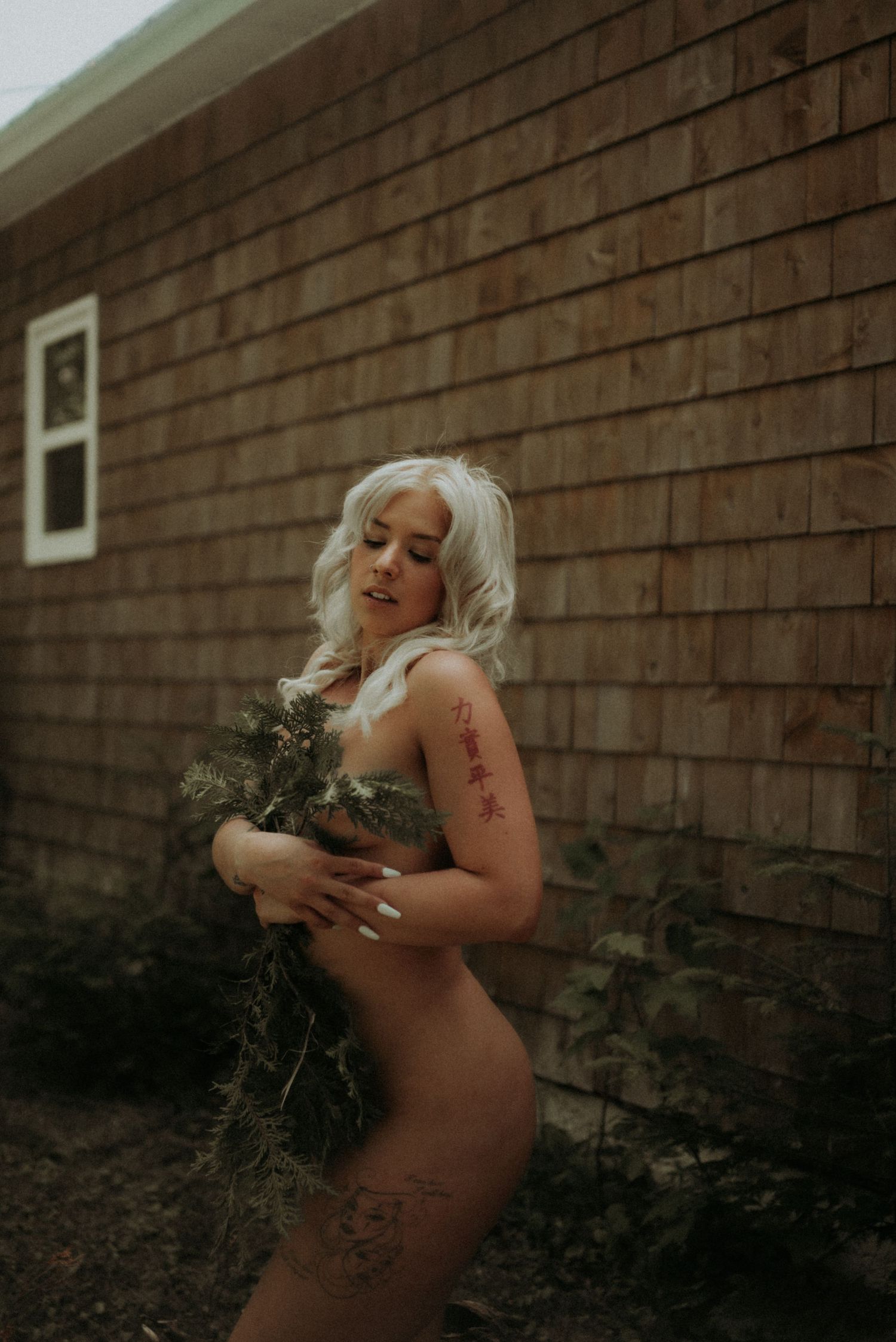 Artistic maternity portrait against wooden siding in natural light.