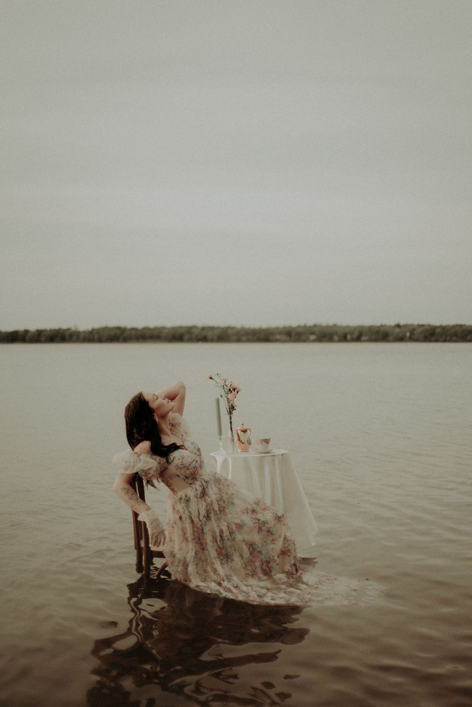 Ethereal water photoshoot with vintage chair and elegant table setting in a serene lake.