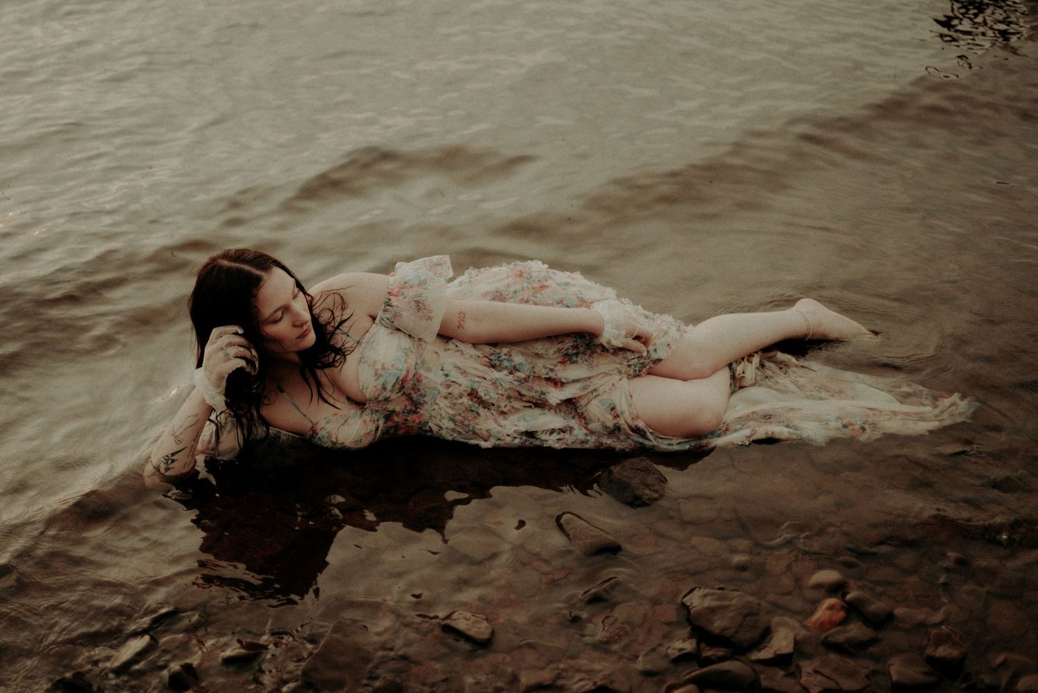 Moody portrait of a person floating in dark waters wearing a vintage dress.