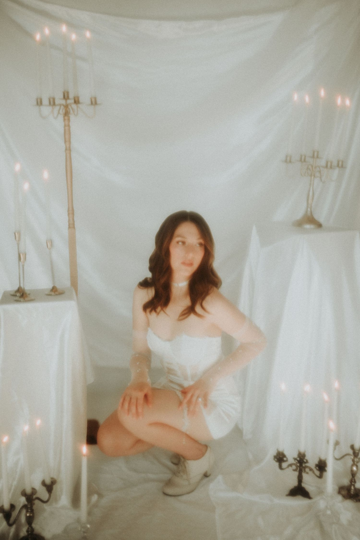 Dreamy photo series with white fabric backdrop, candelabras, and soft lighting creating an ethereal atmosphere.