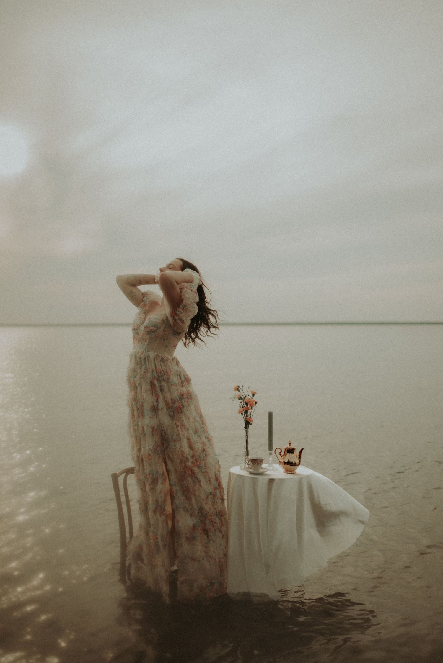 Dramatic water photoshoot with flowing dress and elegant table setup in muted tones.