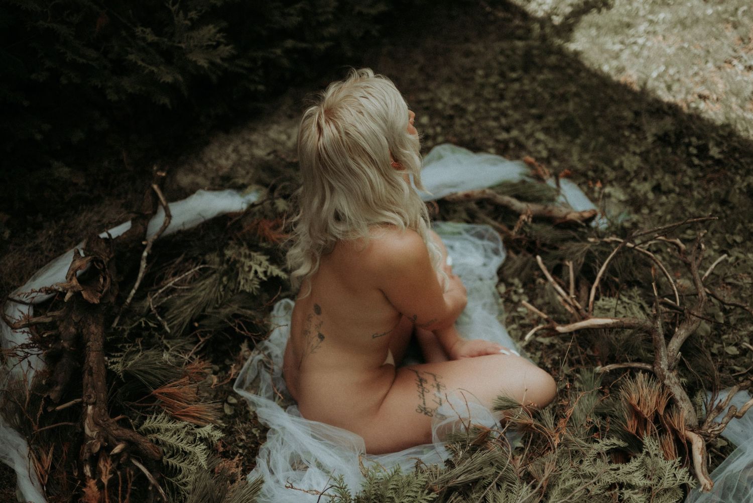 Ethereal outdoor boudoir photography with natural forest elements and soft lighting.