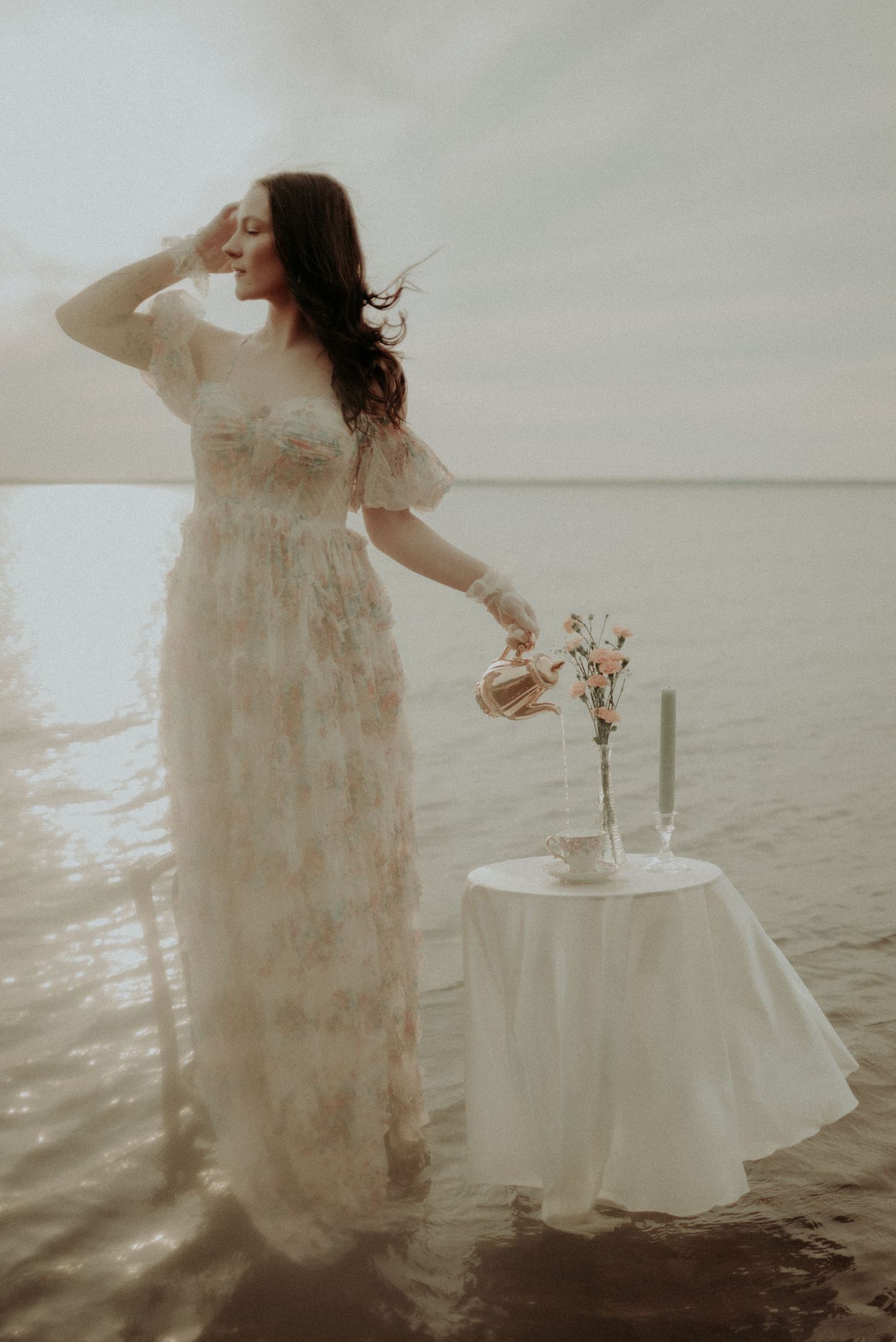 Dramatic water photography featuring flowing dress and elegant table setup in muted colors.