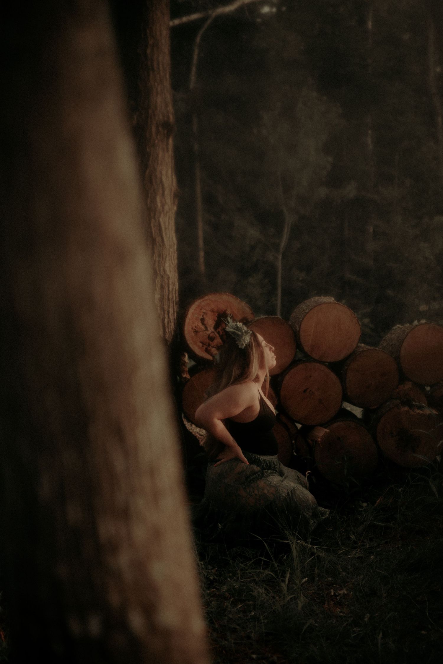 Dramatic low-light forest photography with woodpile and natural poses.
