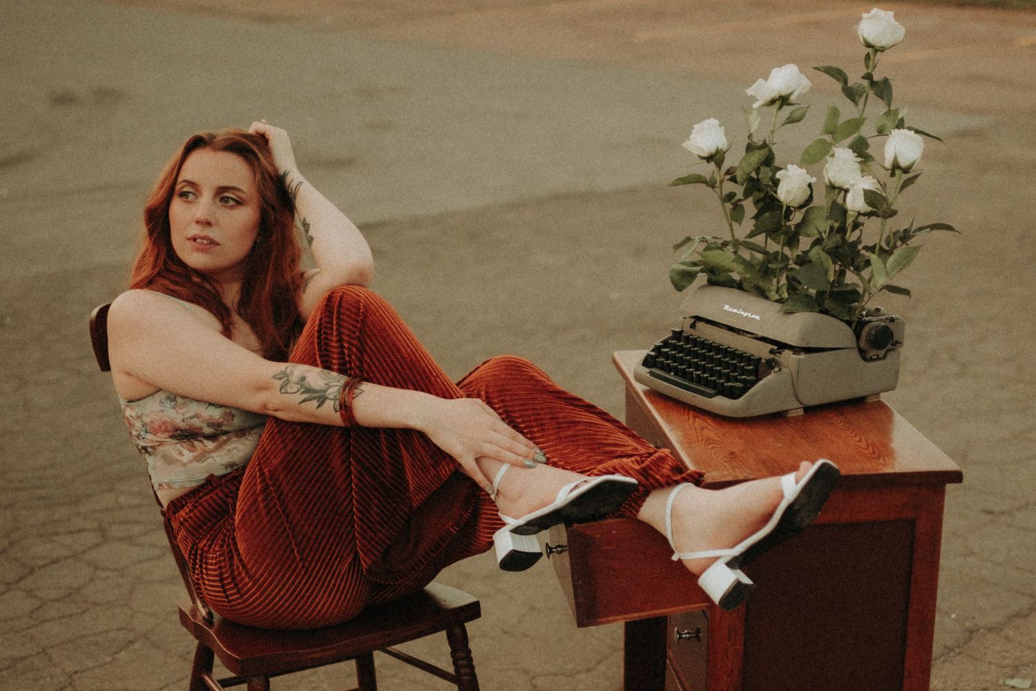 Retro-styled portrait with vintage typewriter and white roses on wooden desk.