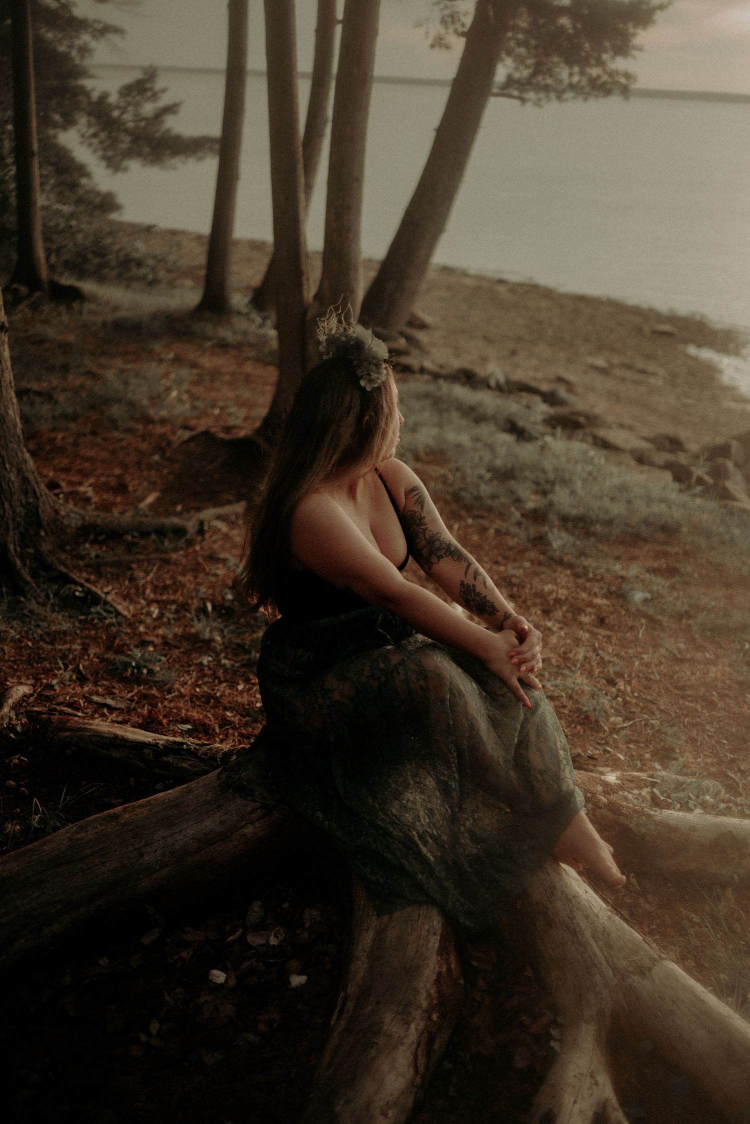 Dreamy forest photoshoot by the water with ethereal lighting and a flowing dress at sunset.