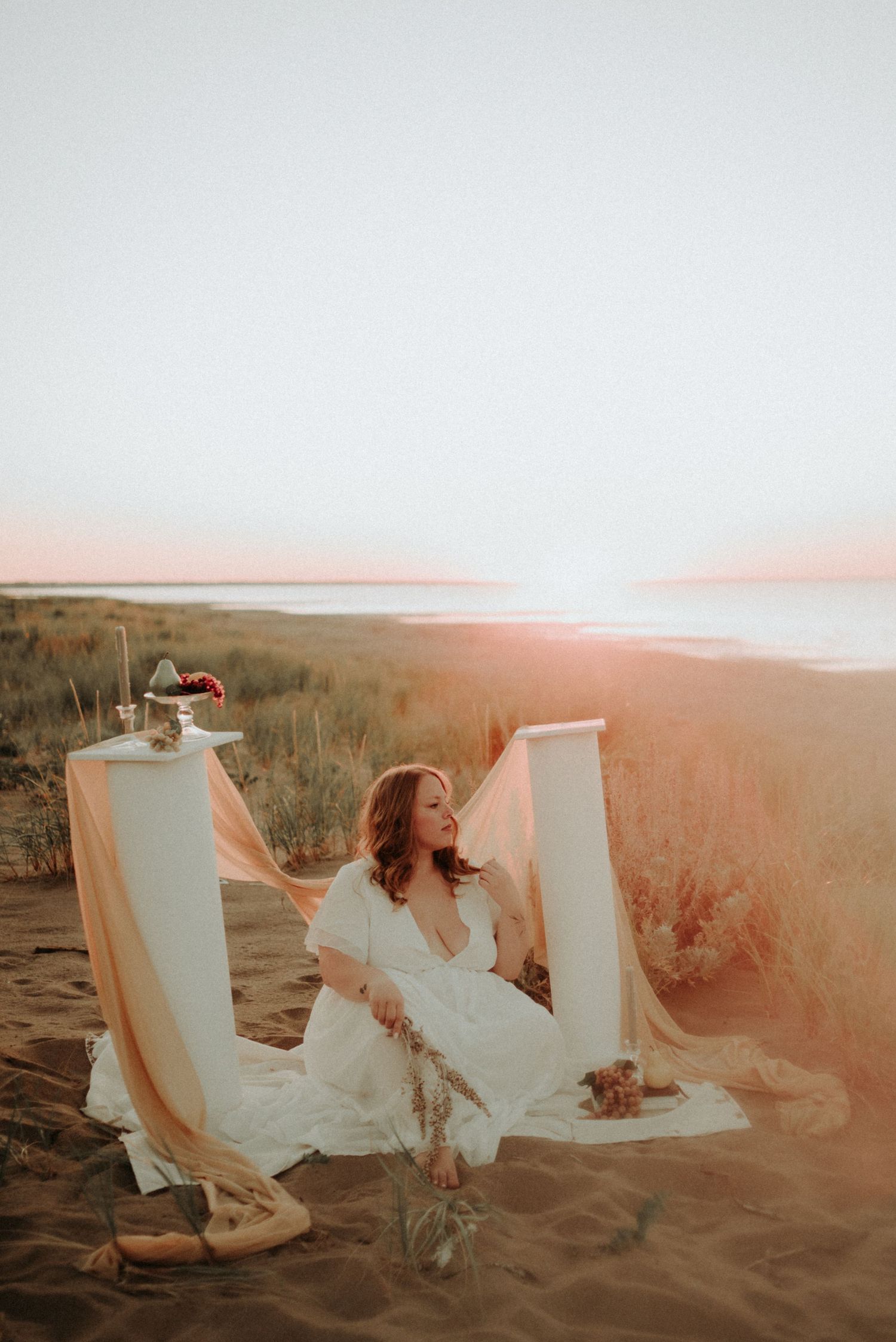 Artistic beach photography with white architectural elements and flowing dress fabric at dusk.