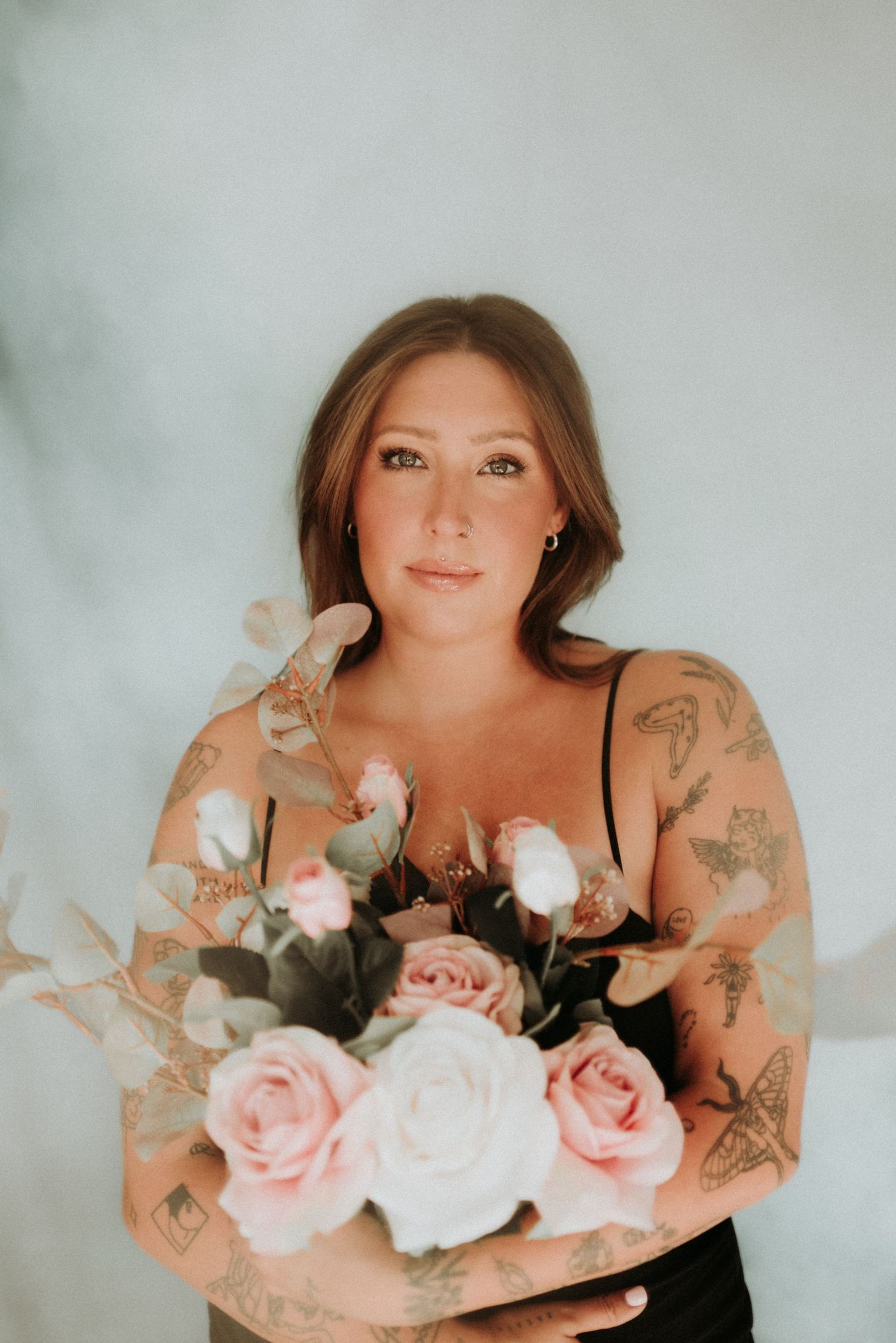 A dreamy boudoir photo series showing someone holding pink and white roses against a light gray background.