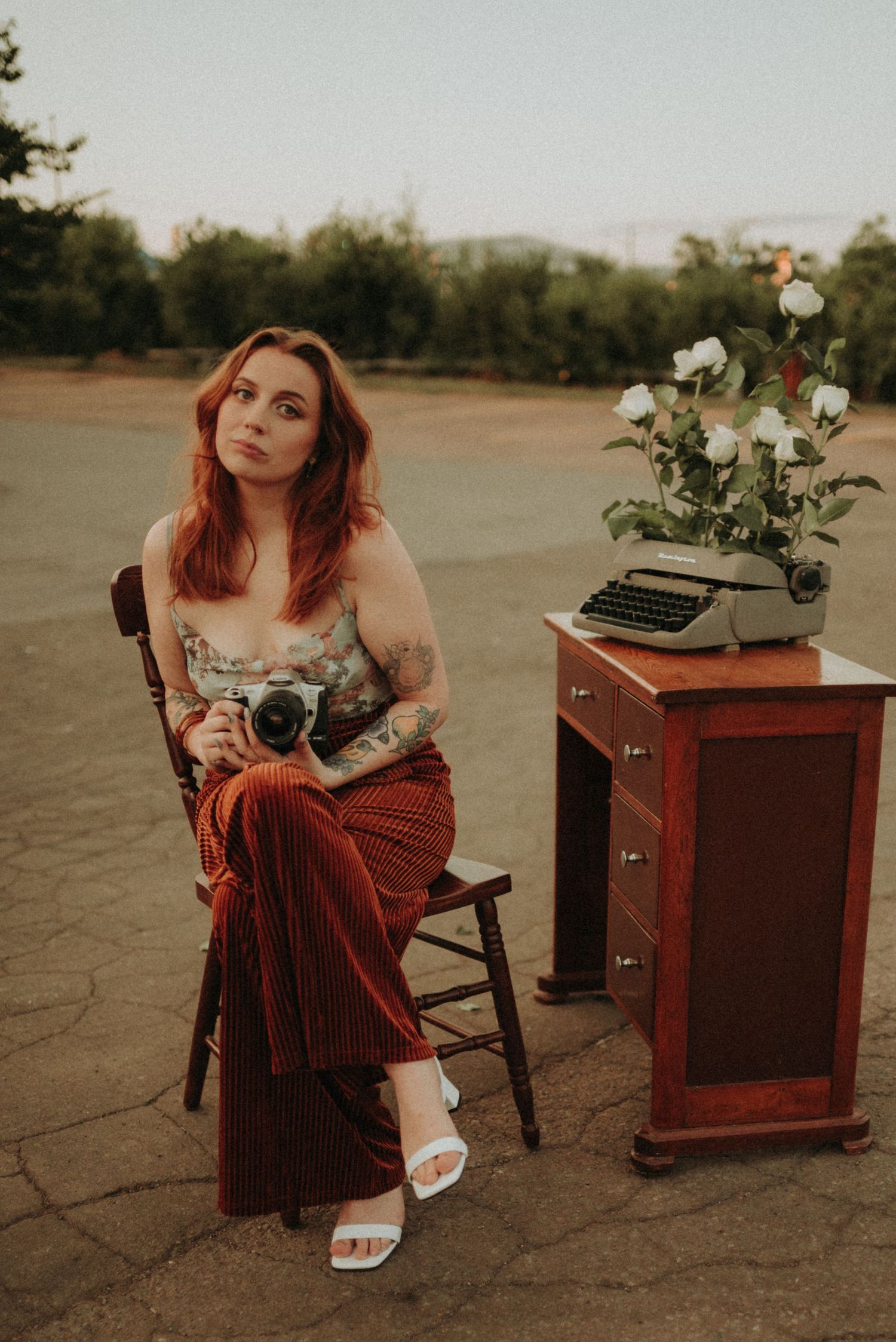 Portrait with vintage camera and typewriter in warm sunset lighting.