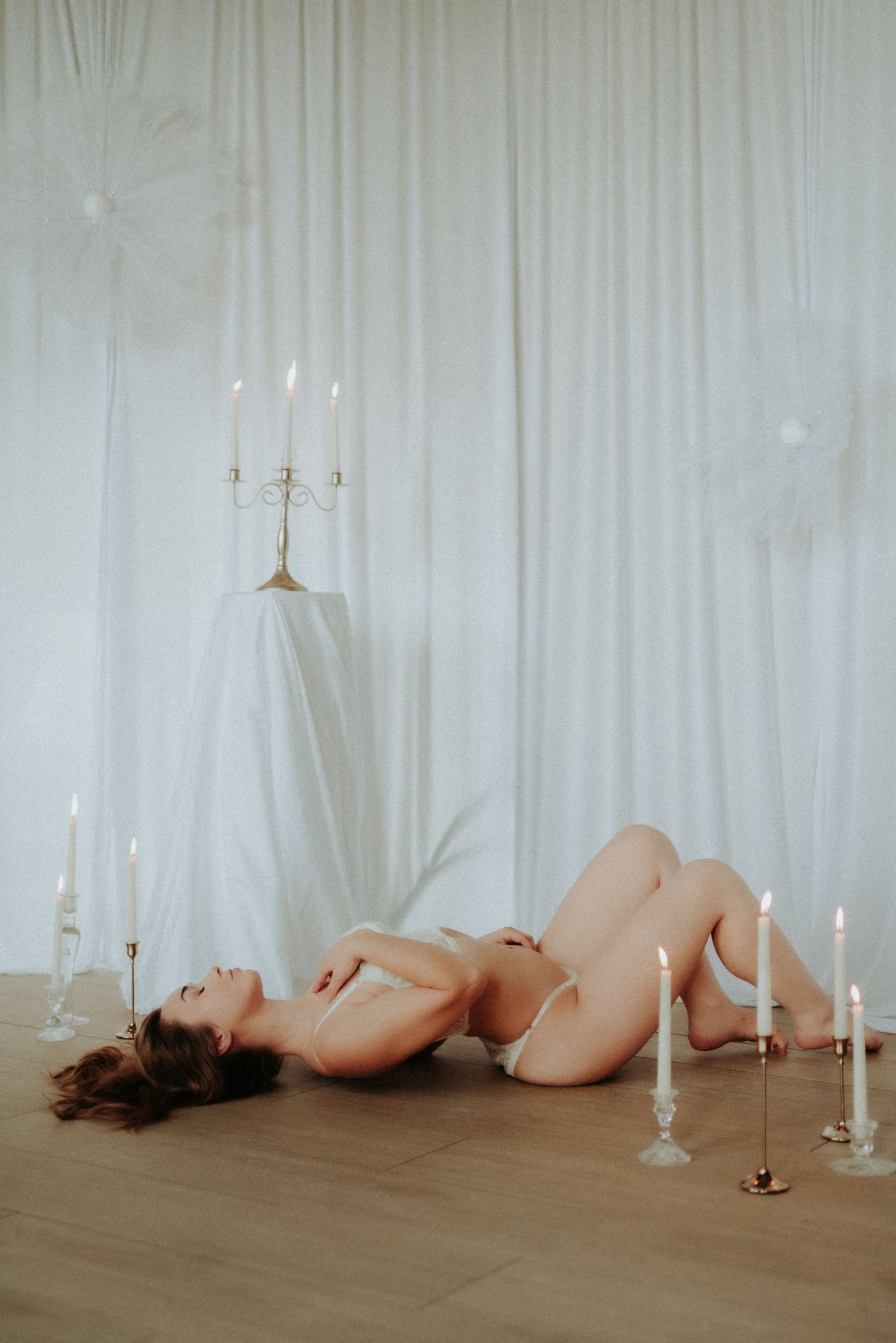 Artistic composition with candlesticks and draped white fabric in studio setting.