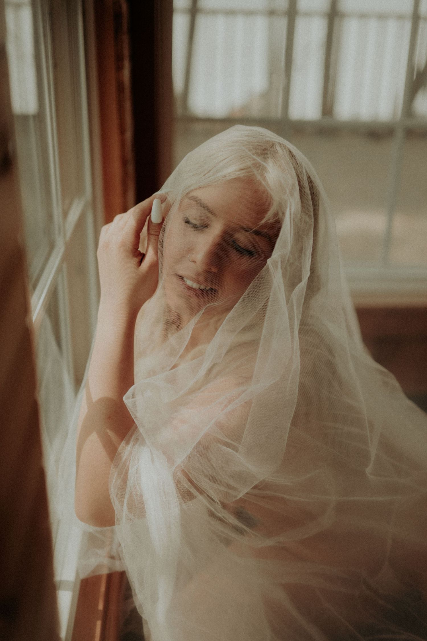 Gentle natural light creates an ethereal mood in intimate portrait with veil.