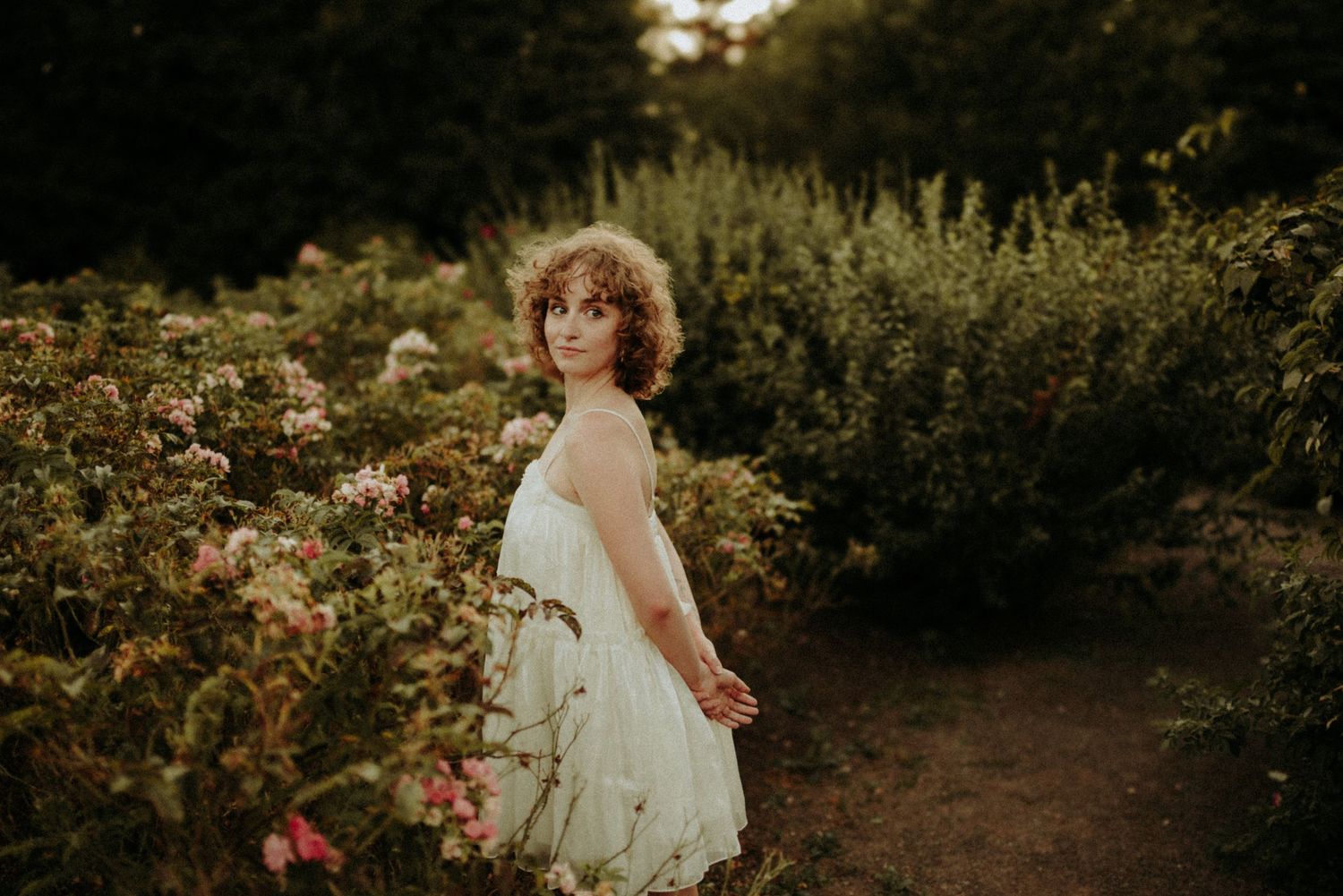 Dreamy sunset photography session among blooming flowers and tall grass in a natural garden setting.
