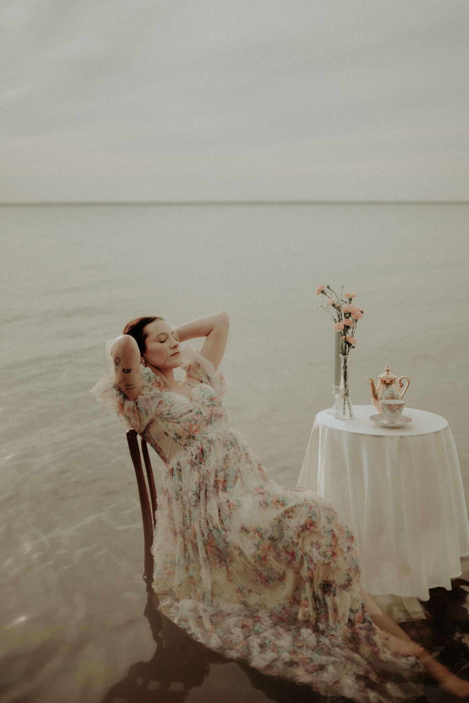 Ethereal scene with a round white table and delicate floral arrangement set in shallow water.