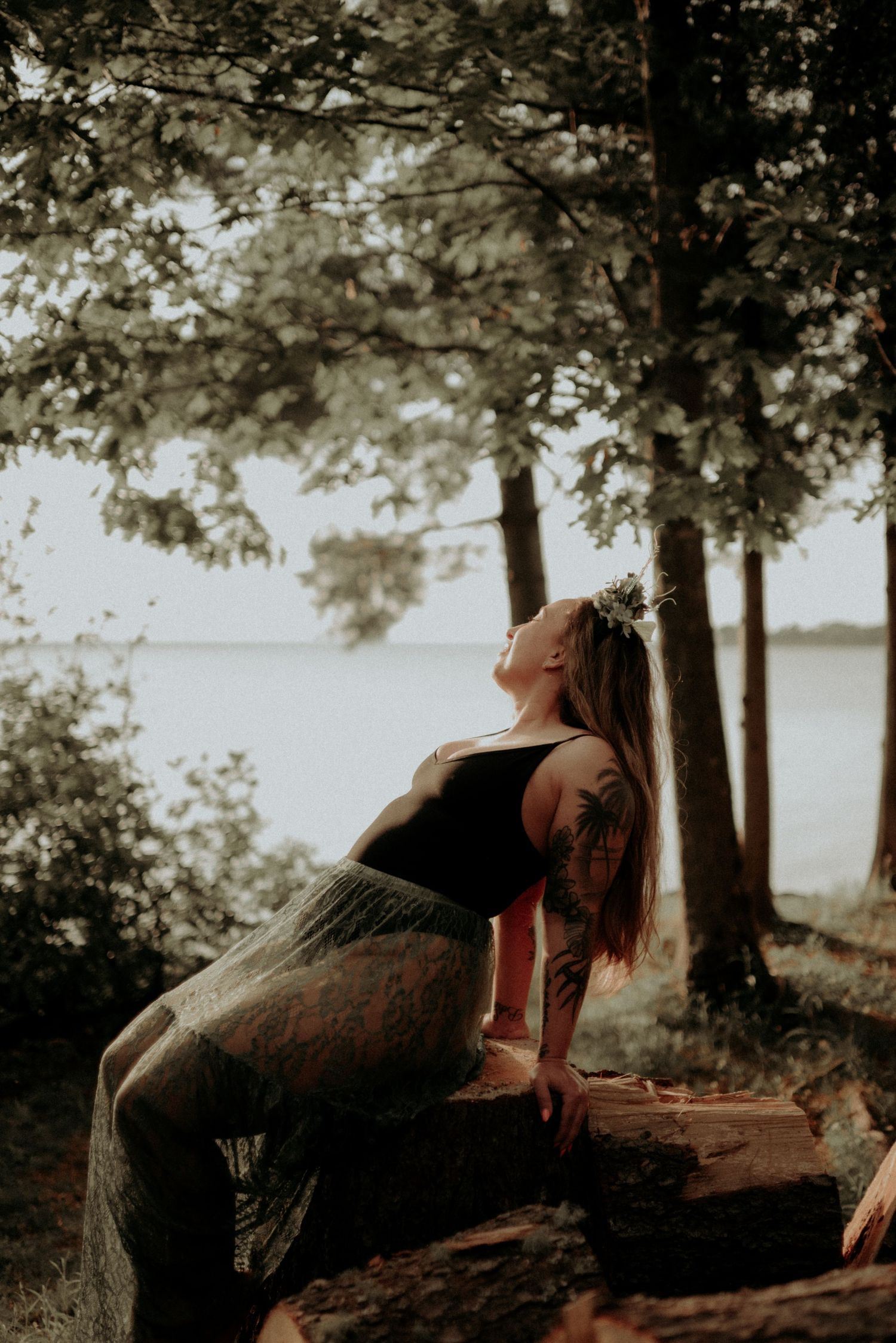 Artistic pose against forest backdrop with lake view in sepia tones.