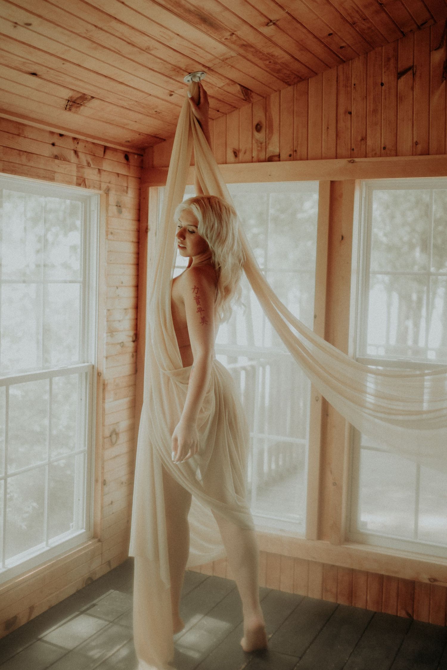 Flowing white fabric creates graceful motion in sunlit cabin interior.