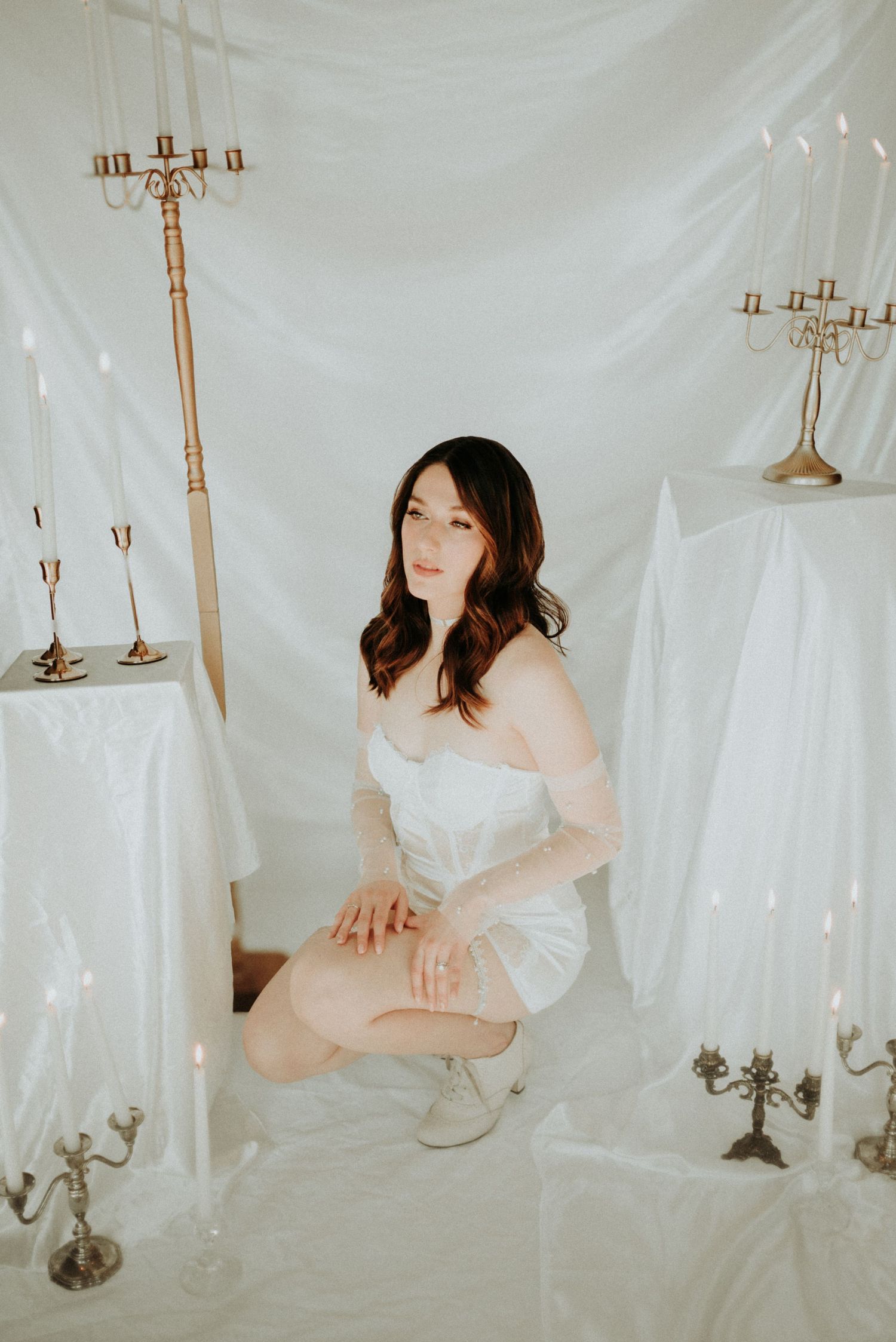 Ethereal studio portraits with white fabric draping and vintage candelabras create a dreamy romantic atmosphere.