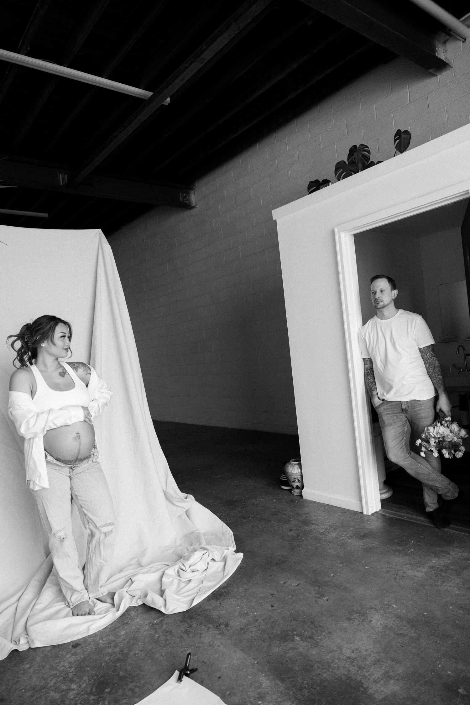Black and white maternity photoshoot in a minimalist studio setting.