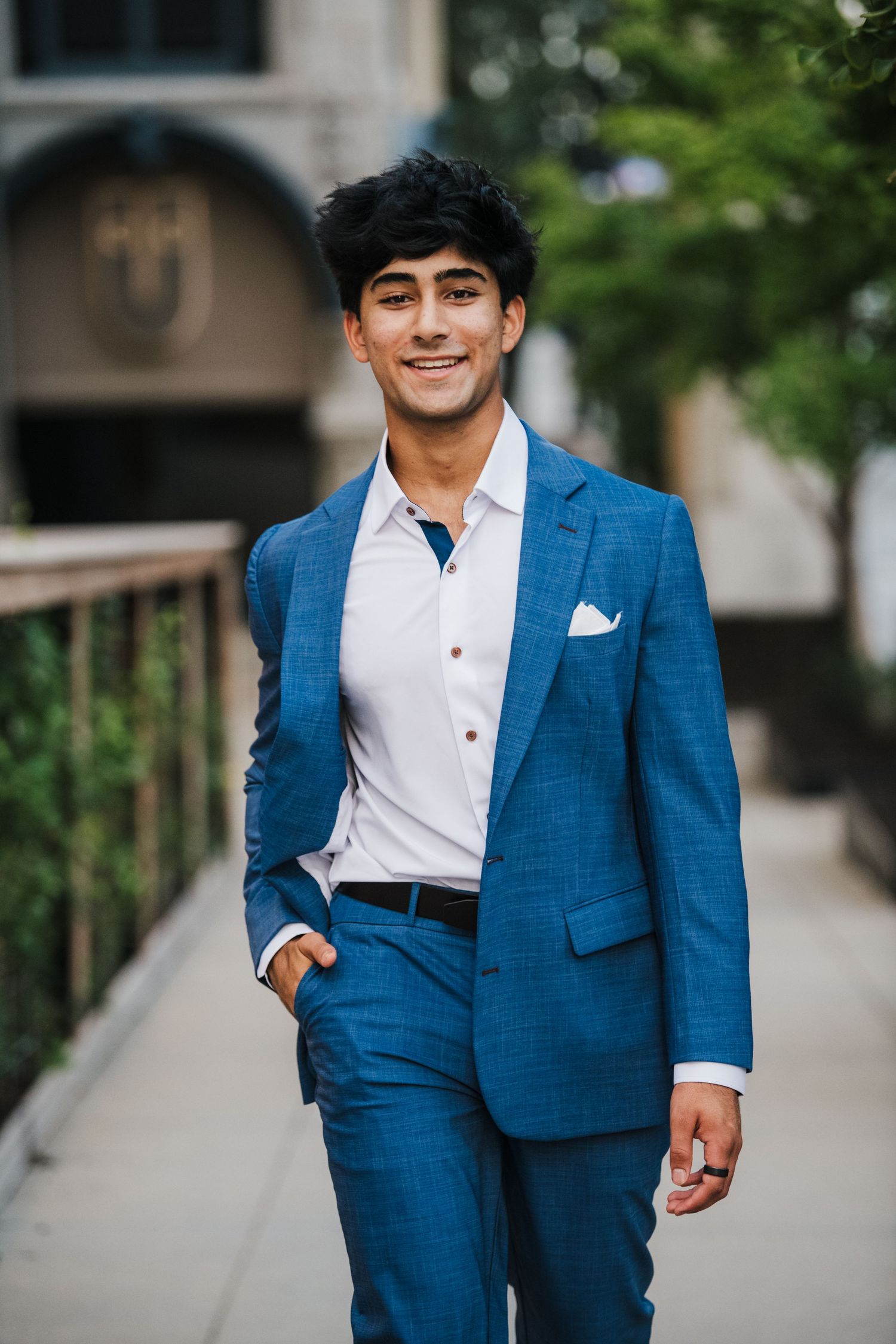 Professional portraits in crisp blue suit and white shirt walking along urban pathway.