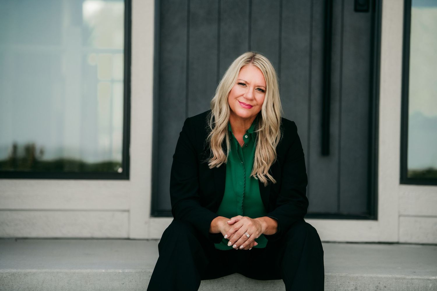 Woman in casual outfit posing outdoors against white building exterior.
