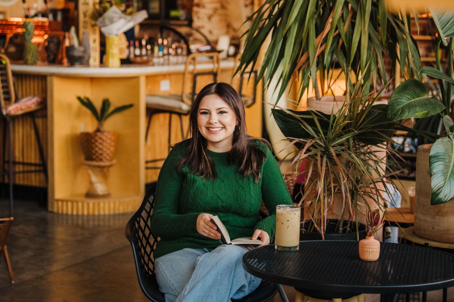 Cozy indoor portrait of someone relaxing in green sweater among plants.
