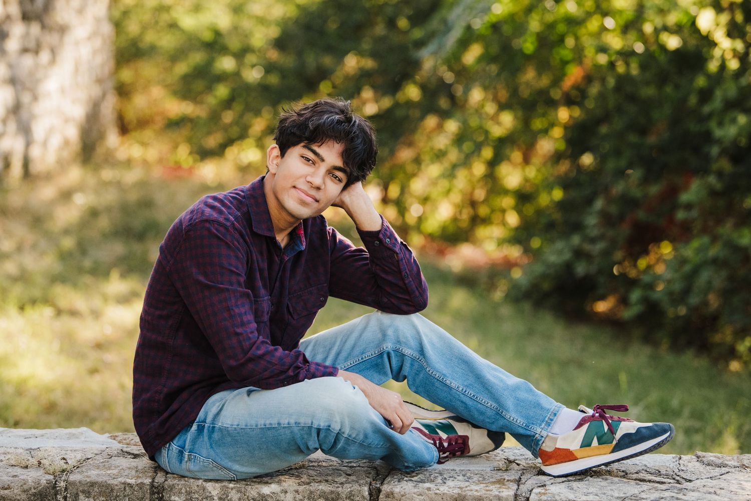 Casual outdoor photo shoot with denim and purple sweater on stone surface.