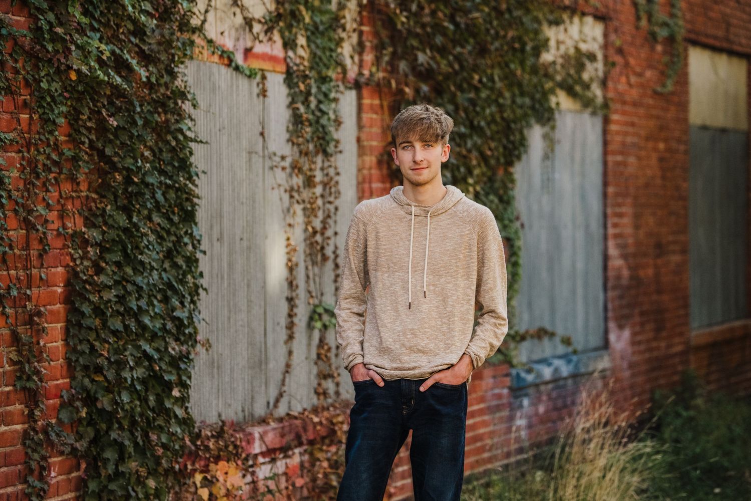 Casual portrait session against brick wall with climbing ivy background.