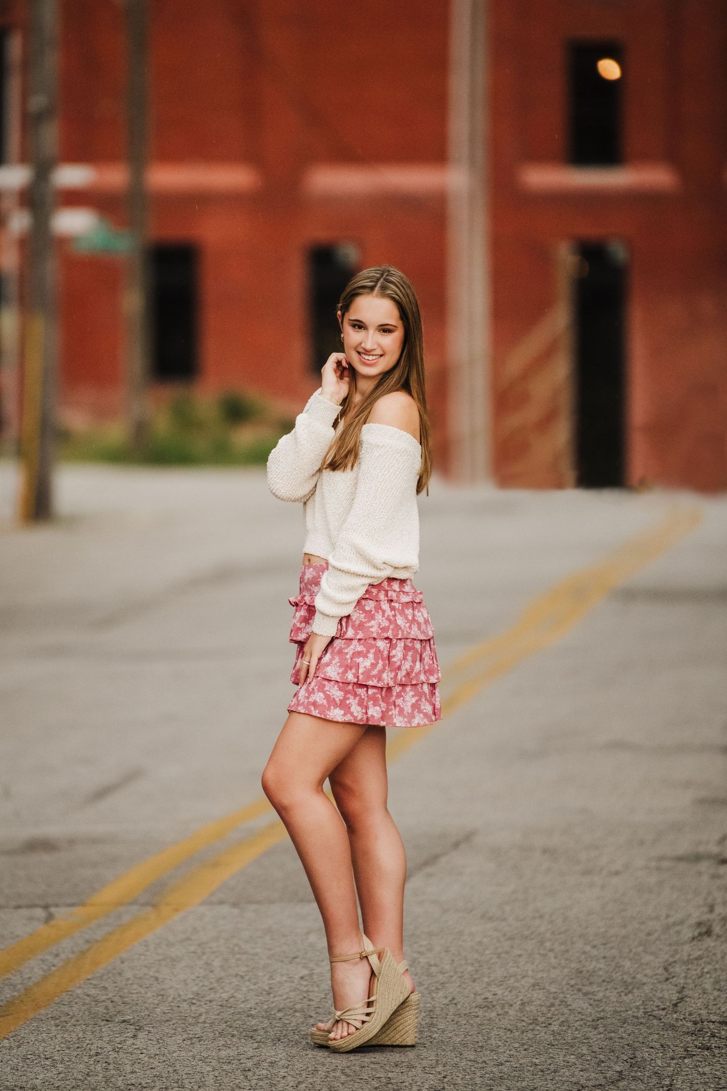 Fashion portrait on city street featuring white sweater and pink ruffled skirt.