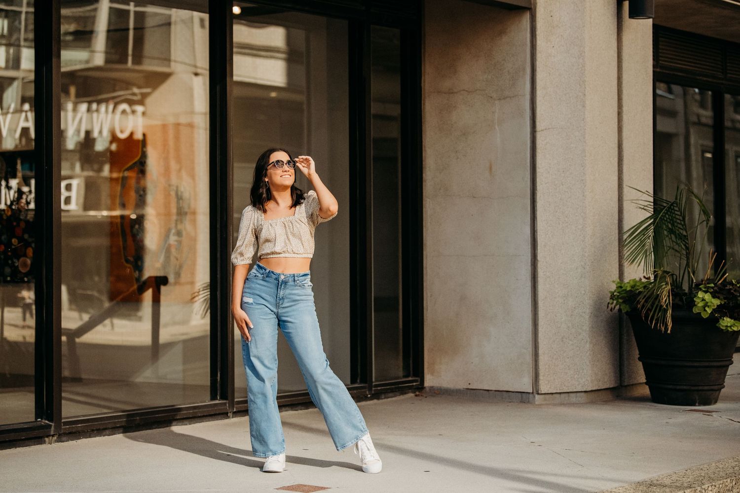 Urban fashion shoot outside modern building with glass windows and concrete columns.