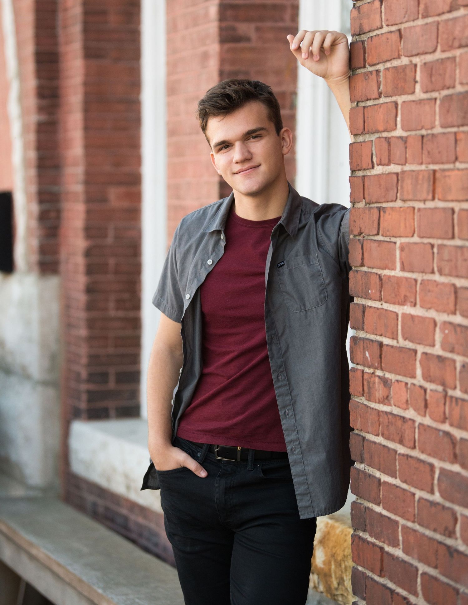 Professional portrait session against brick wall backdrop showing casual modern menswear styling.