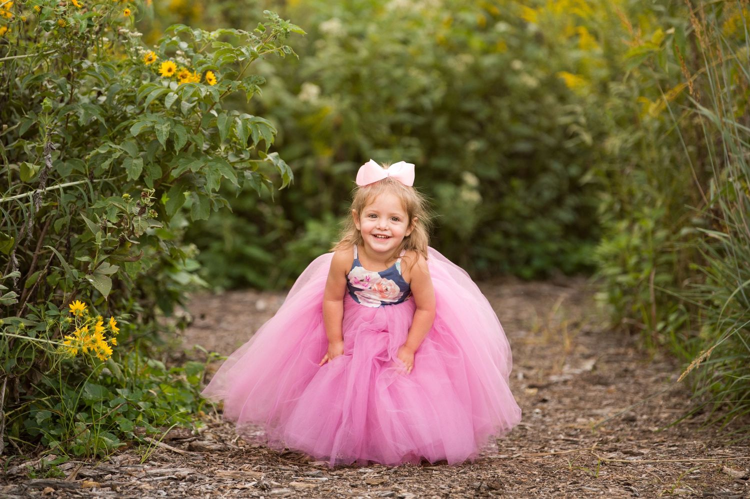A series of outdoor photos showing a pink tulle dress in a wooded setting with yellow wildflowers in the background.