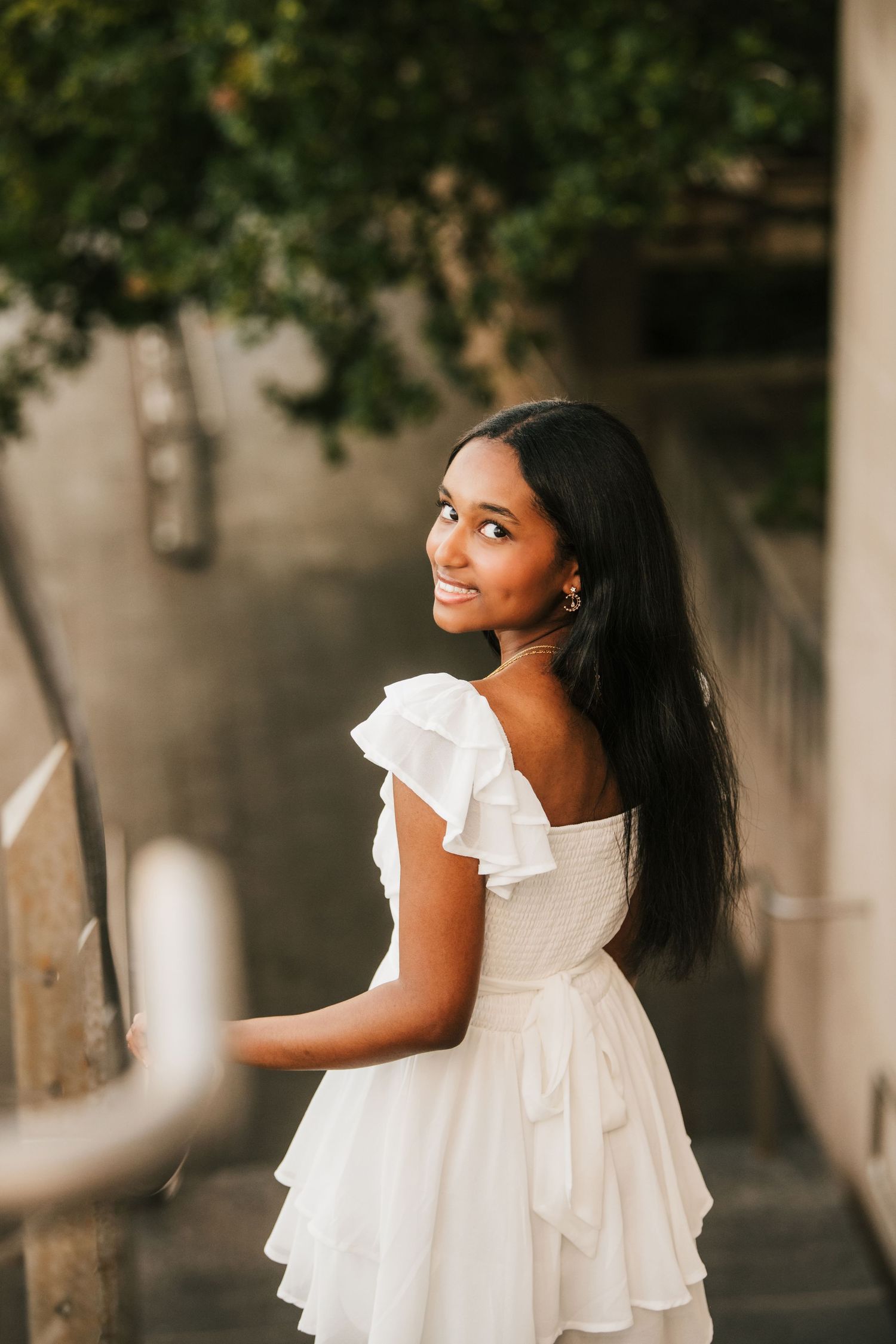 Person in flowing white dress poses gracefully outdoors.
