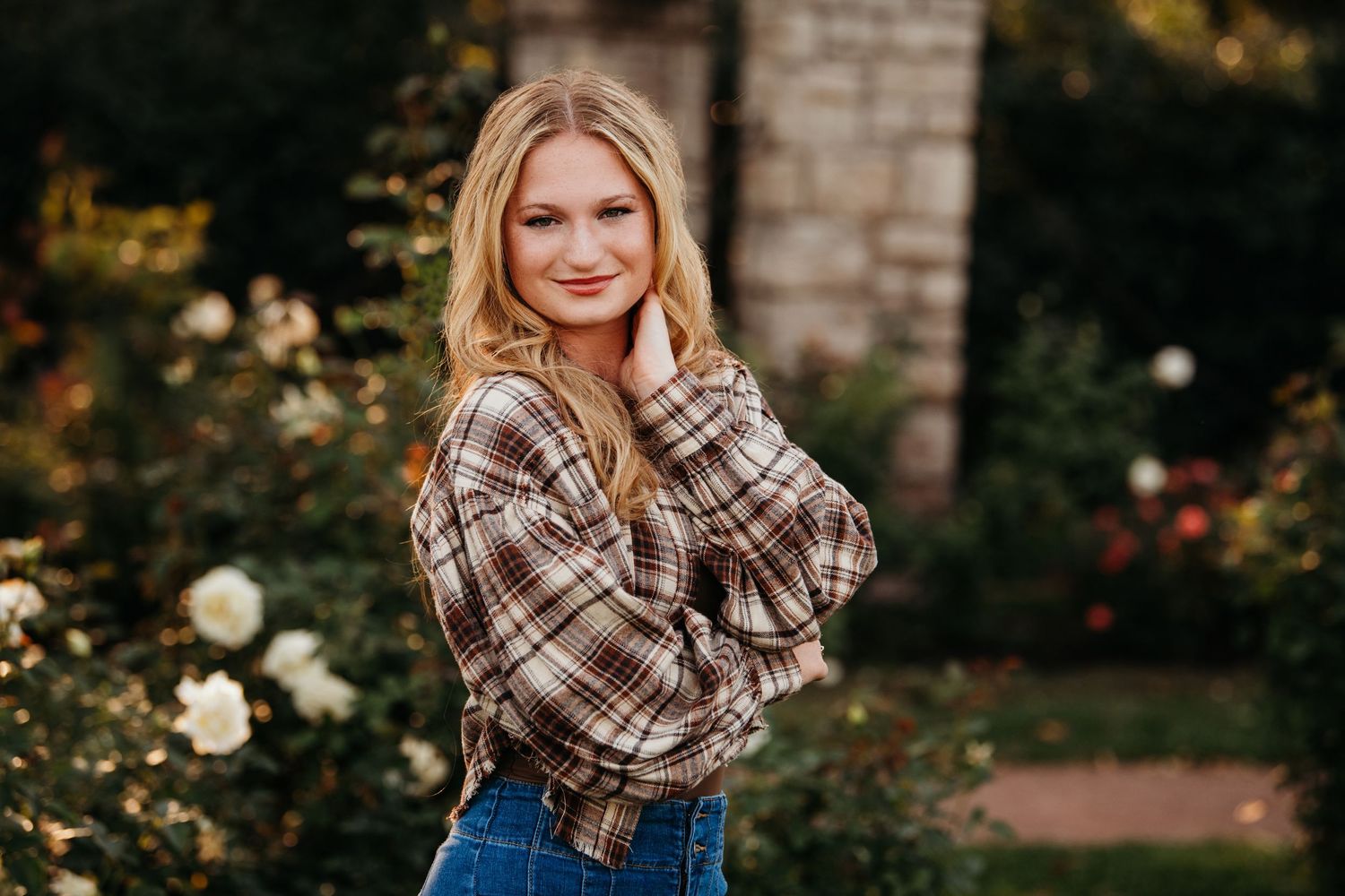 Autumn outdoor portrait session featuring a plaid scarf and casual style against brick wall backdrop.