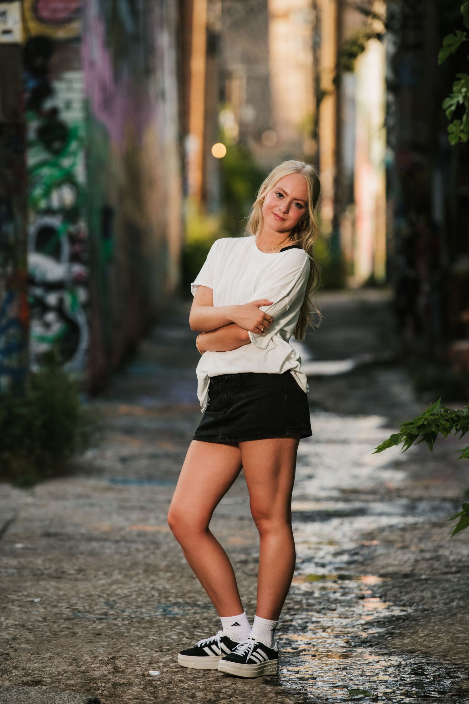 Urban alley photoshoot with casual black and white athletic wear styling.