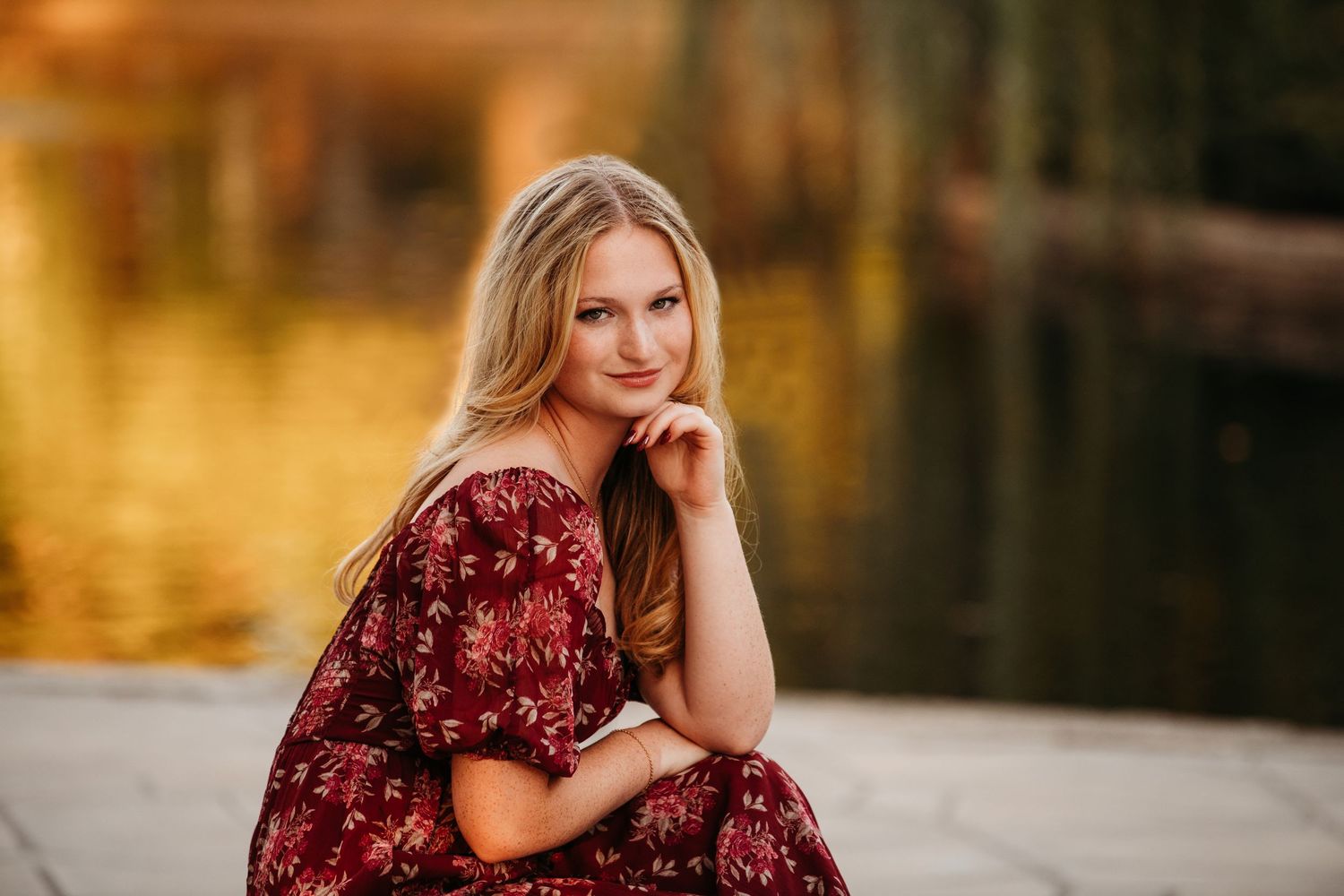 Outdoor portrait session in burgundy floral dress during golden hour.