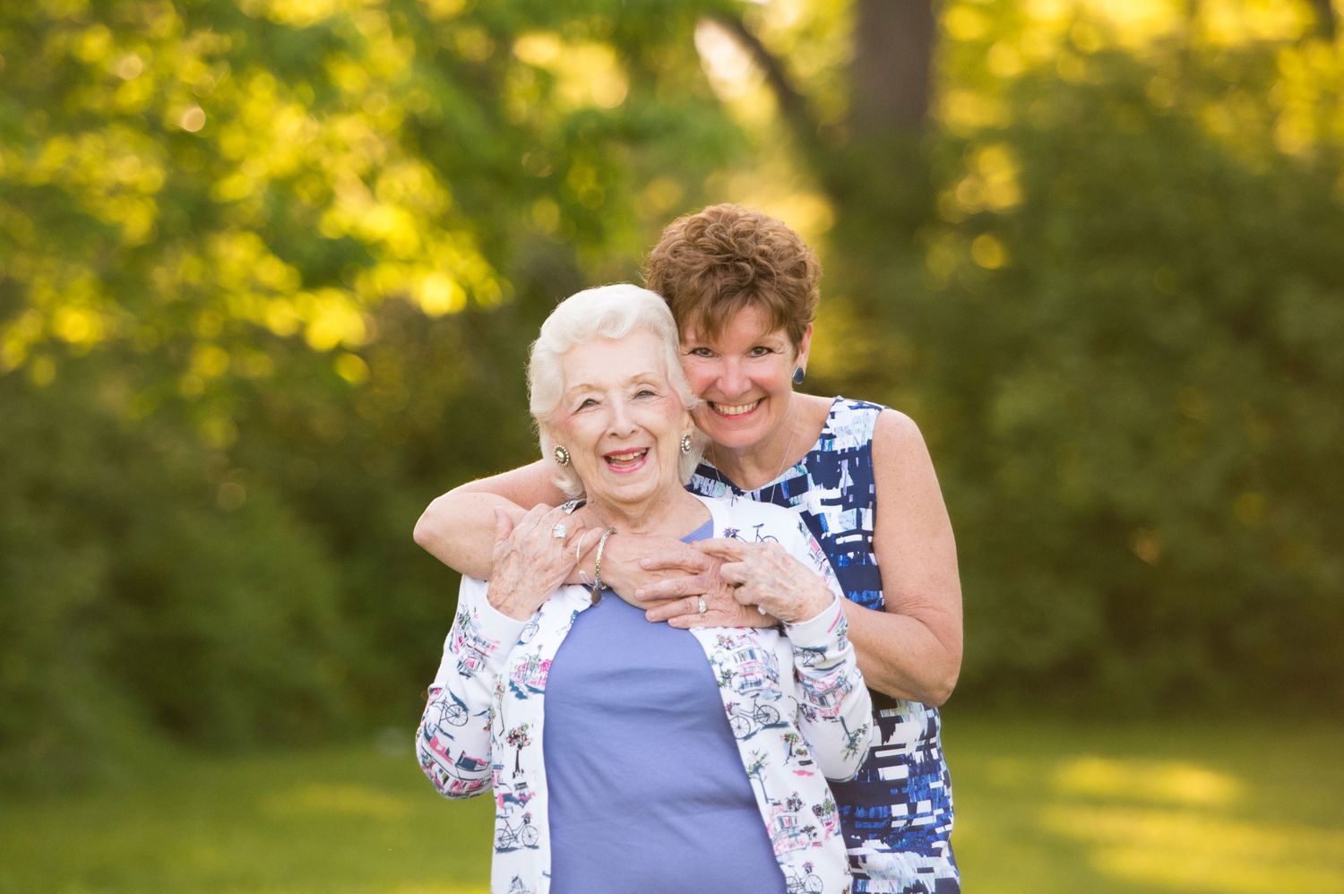 Two people share a joyful moment together outdoors with golden sunlit trees in the background.