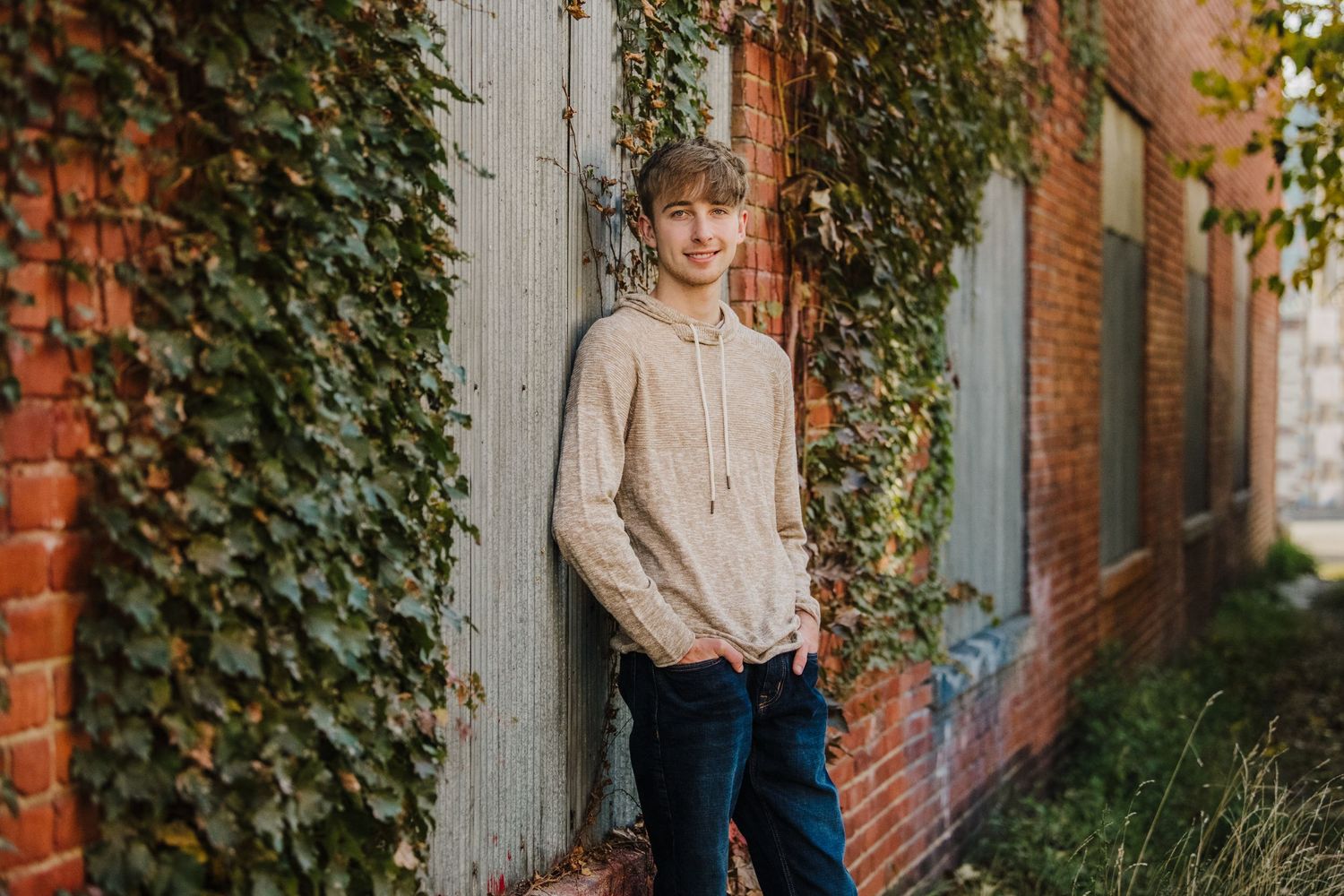 Portrait session against ivy-covered brick wall with natural autumn lighting.