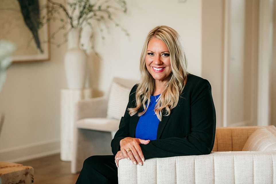 Professional real estate agent in business attire showing modern luxury home interior to potential buyers.