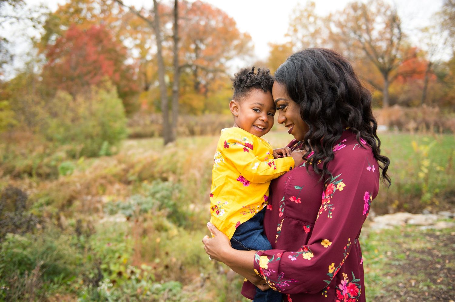 A joyful moment shared between two people embracing outdoors during autumn with colorful fall foliage in the background.