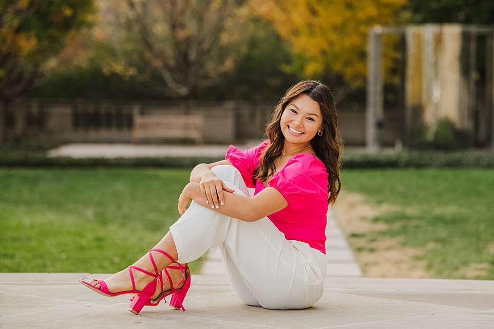Outdoor portrait of someone in bright pink top and white pants with matching pink heels.