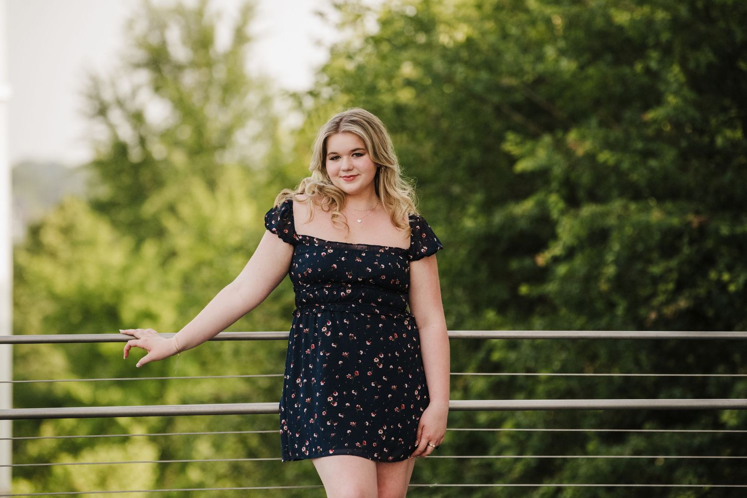 Summer portrait session in polka dot dress against green outdoor background.