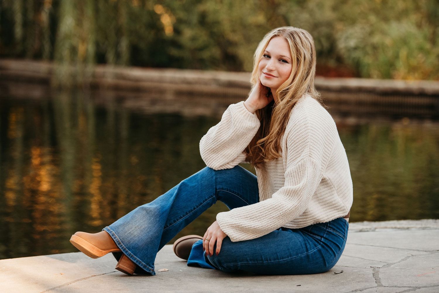 Casual waterfront portrait session with person in white sweater and jeans.