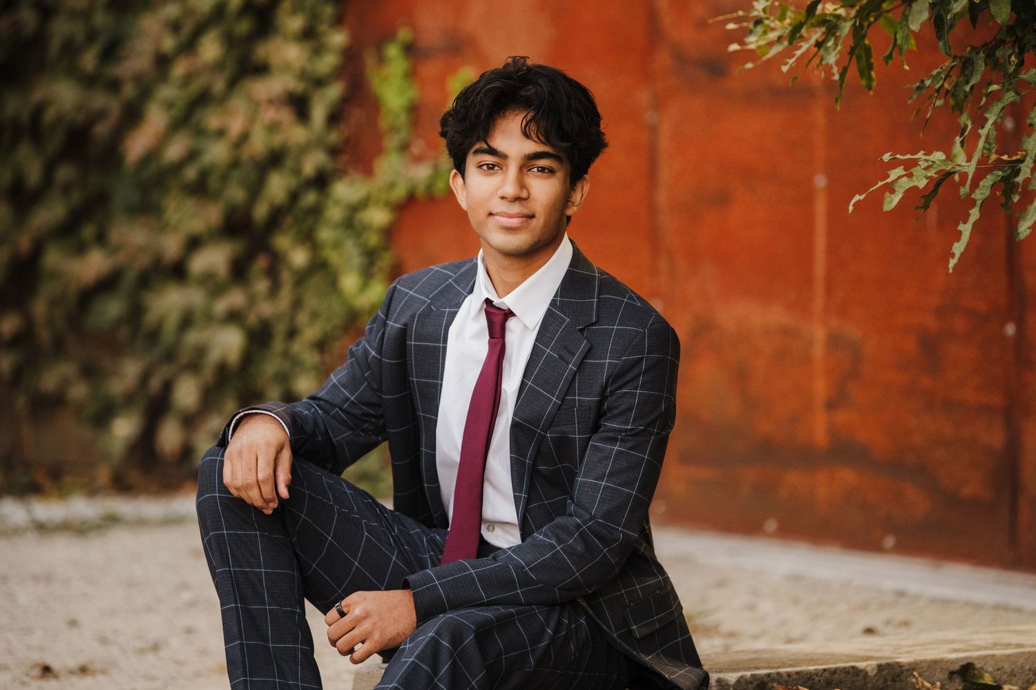 Professional portraits in formal suit and tie against autumn brick backdrop.