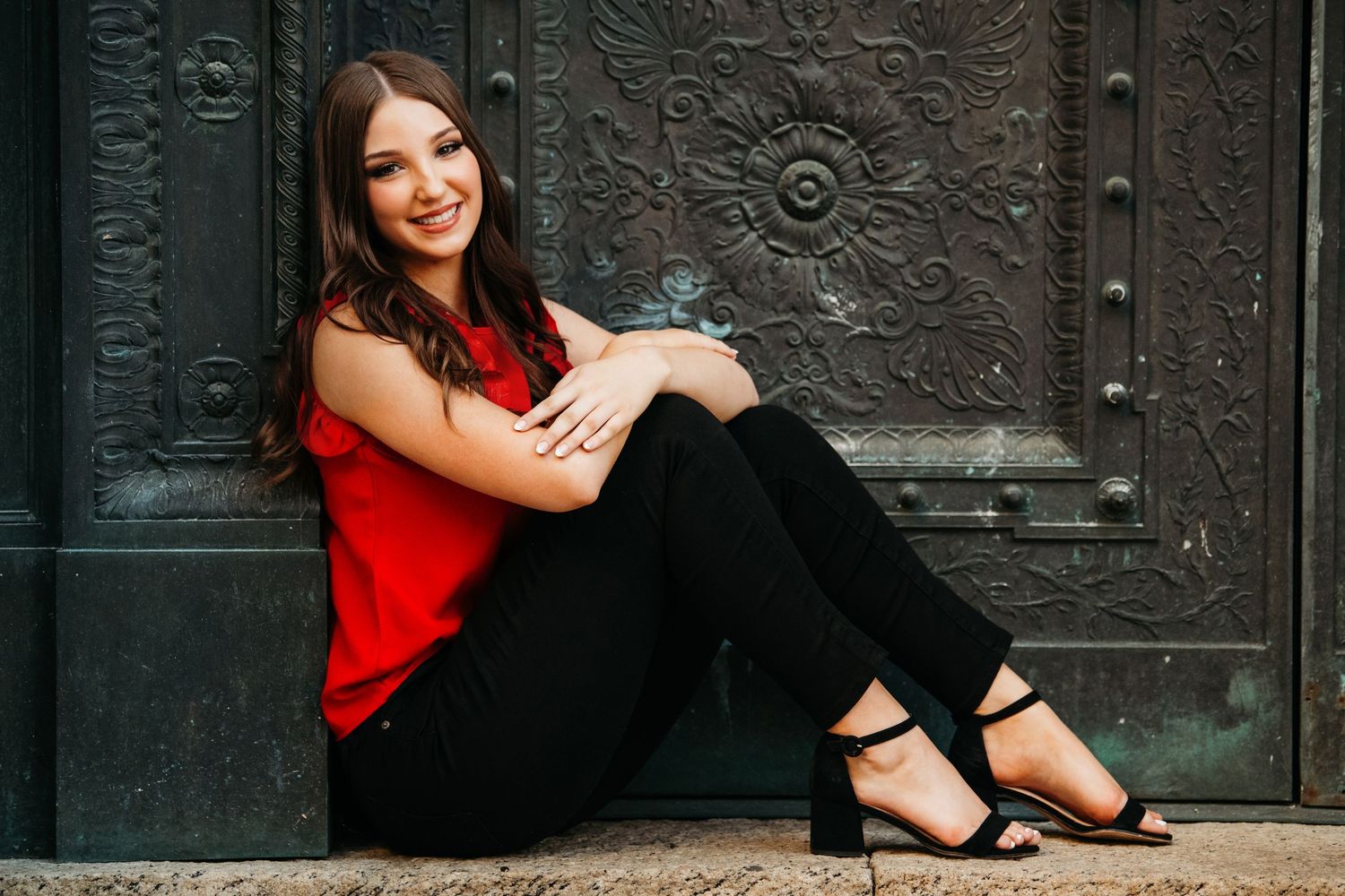 Portrait series against ornate dark wooden door wearing red and black casual outfits.