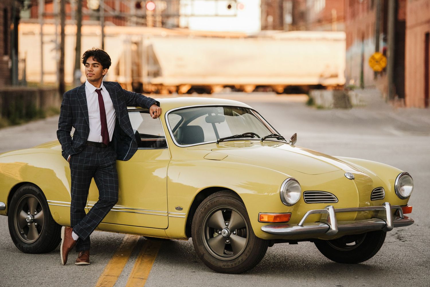 Fashion portrait with vintage yellow Porsche car in urban setting.