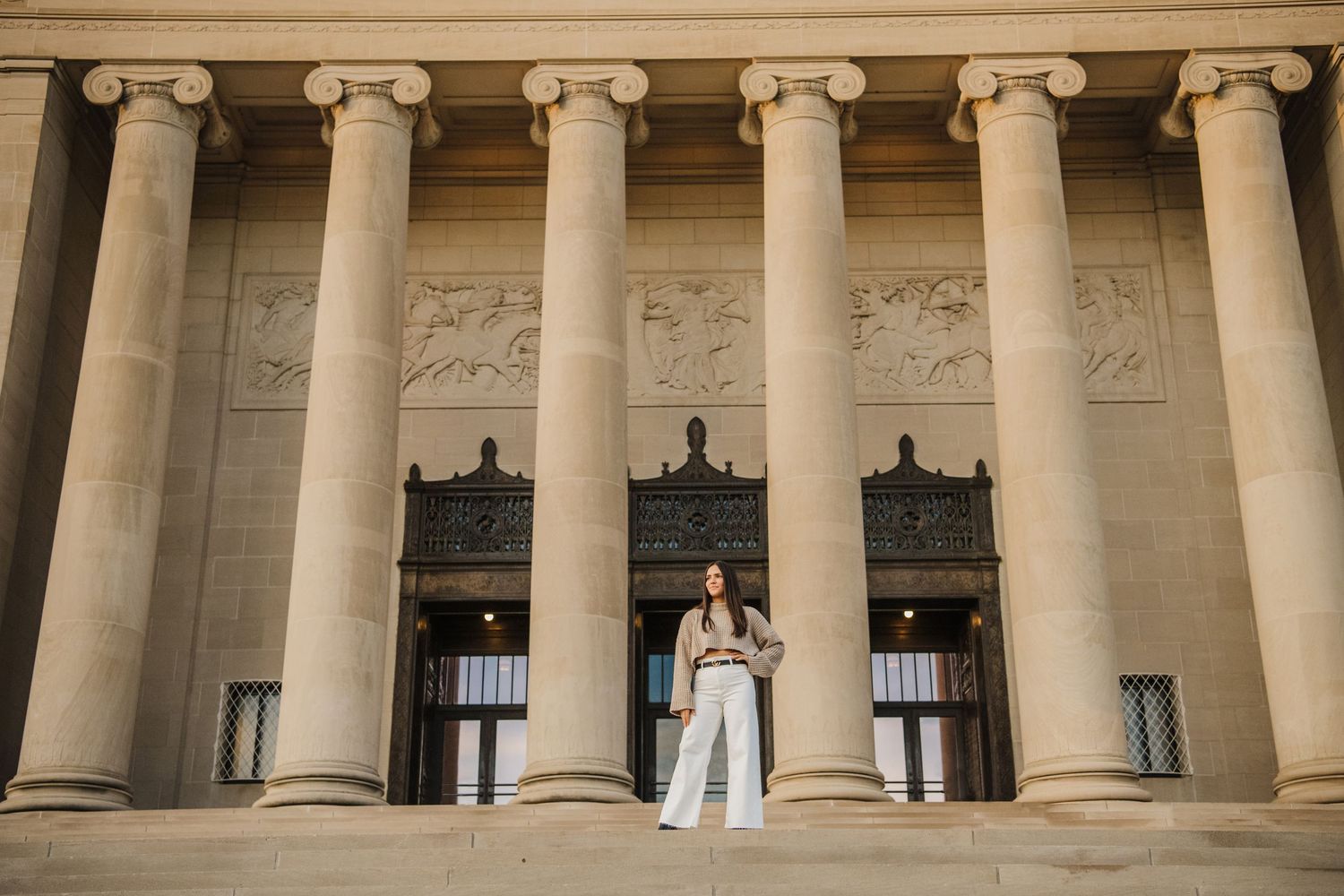 Row of classical stone columns with ornate capitals against bright sky.
