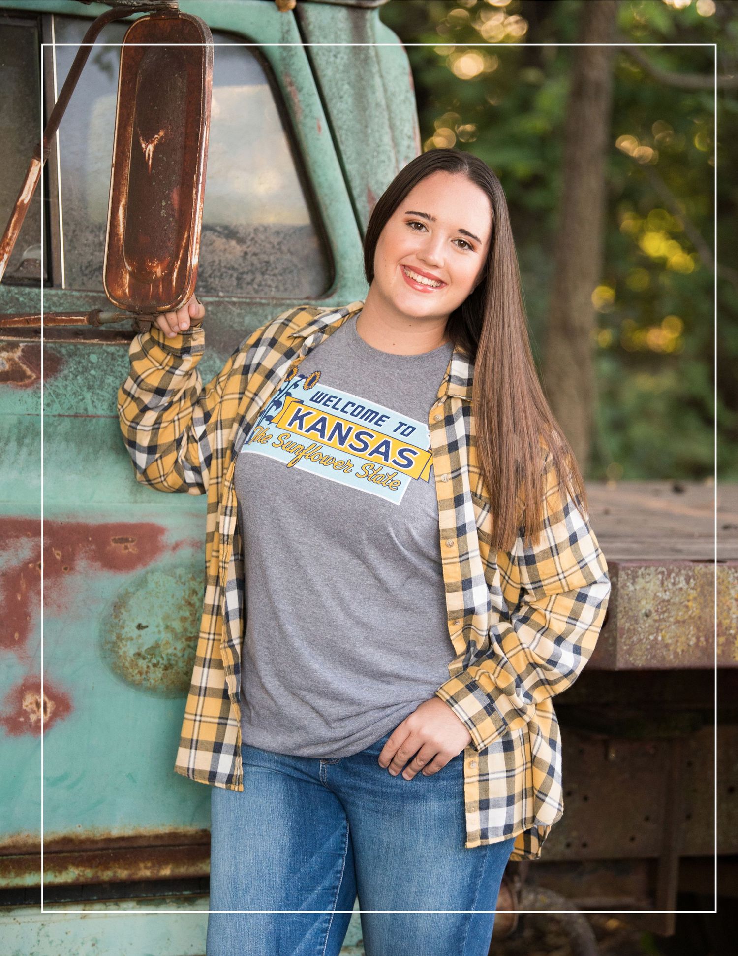 Senior portrait featuring casual style with yellow plaid shirt and Kansas graphic tee.