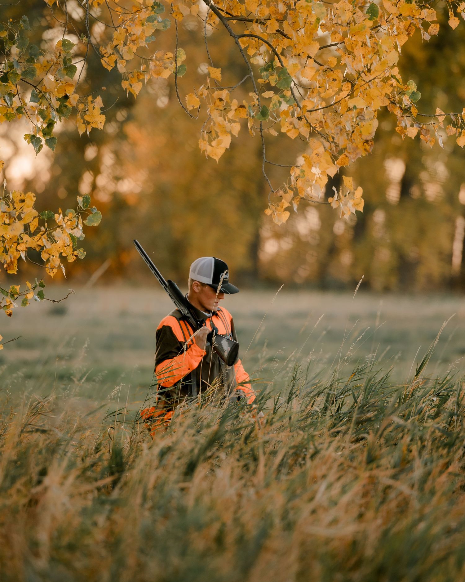 High school senior boy on family farm near Willow Lake, South Dakota with tractor and hunting gear